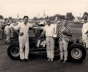 Ron Barton, left, in victory lane after a win at the Clay County Fair in Spencer, IA. Driver Jim Edgington holds the trophy, while Roger Hendrickson holds his hat. 